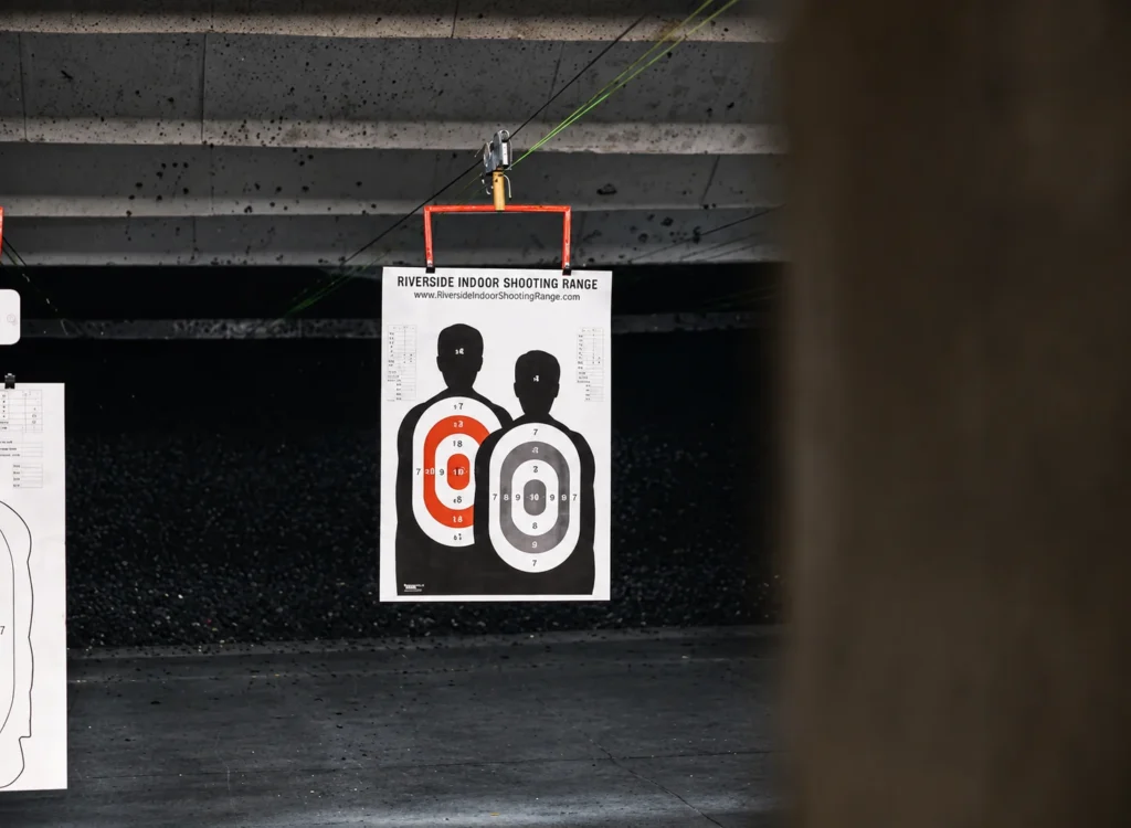 Paper silhouette target hanging inside an indoor shooting range for firearms training and target practice at Old Town Tactical.